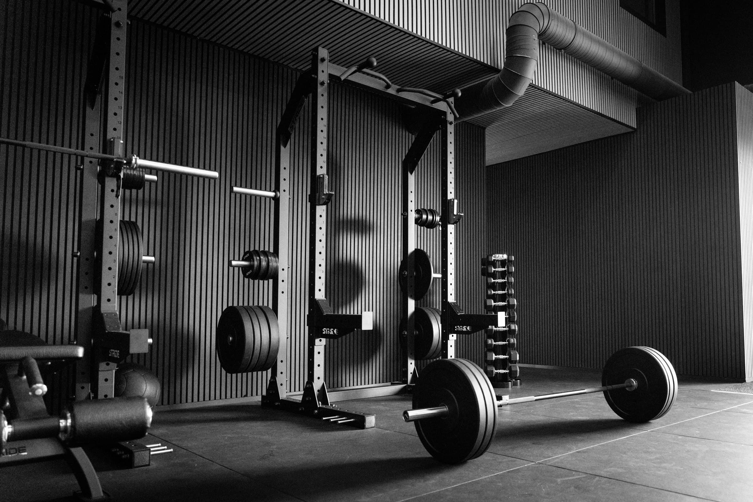 A coach spotting a member mid-lift on the gym floor at Iron Elite